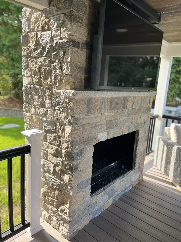 Stacked natural stone outdoor fireplace on a covered porch